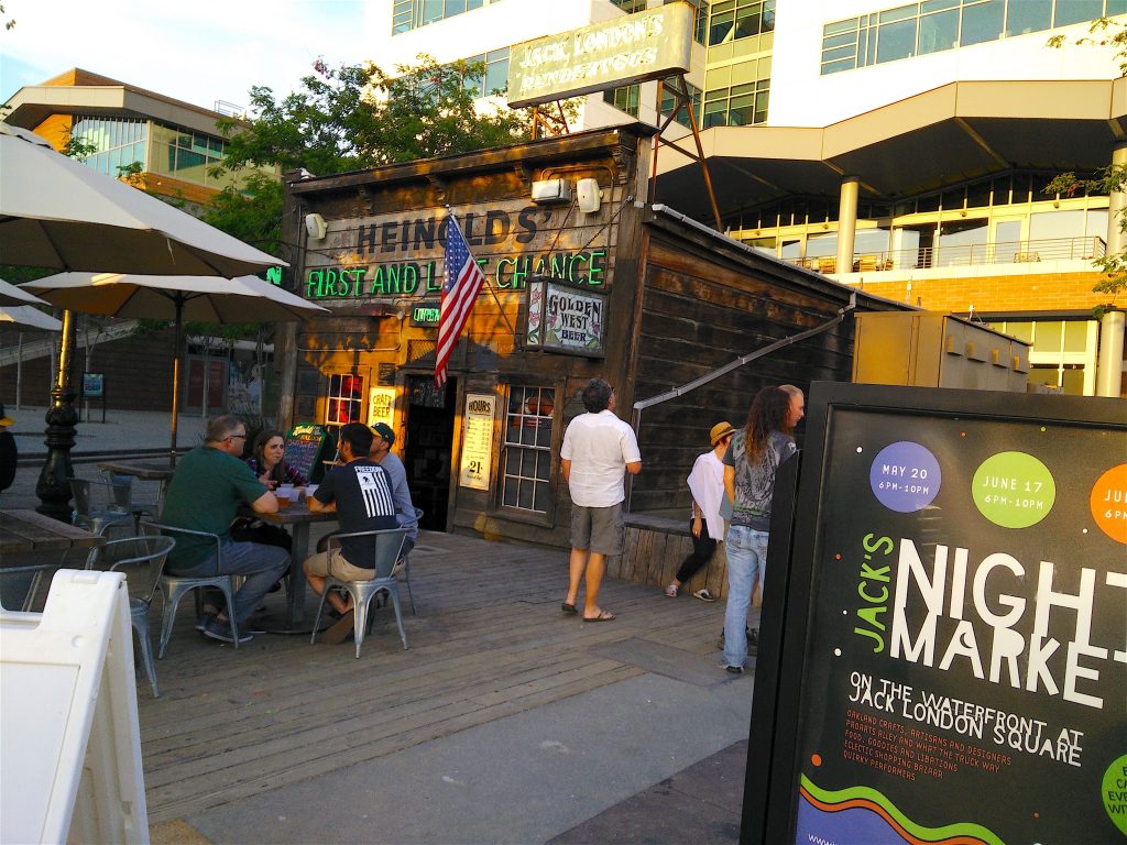 Heinold’s First and Last Chance Saloon, people sitting outdoors, people at a pub, bar in Jack London Square, Oakland, historic pub, Jack London Square, Jack London, San Francisco, bars in Oakland, American literature, American culture, literary San Francisco, outdoor café, streetside pub, street life in Oakland, street life in America, American flag, travel