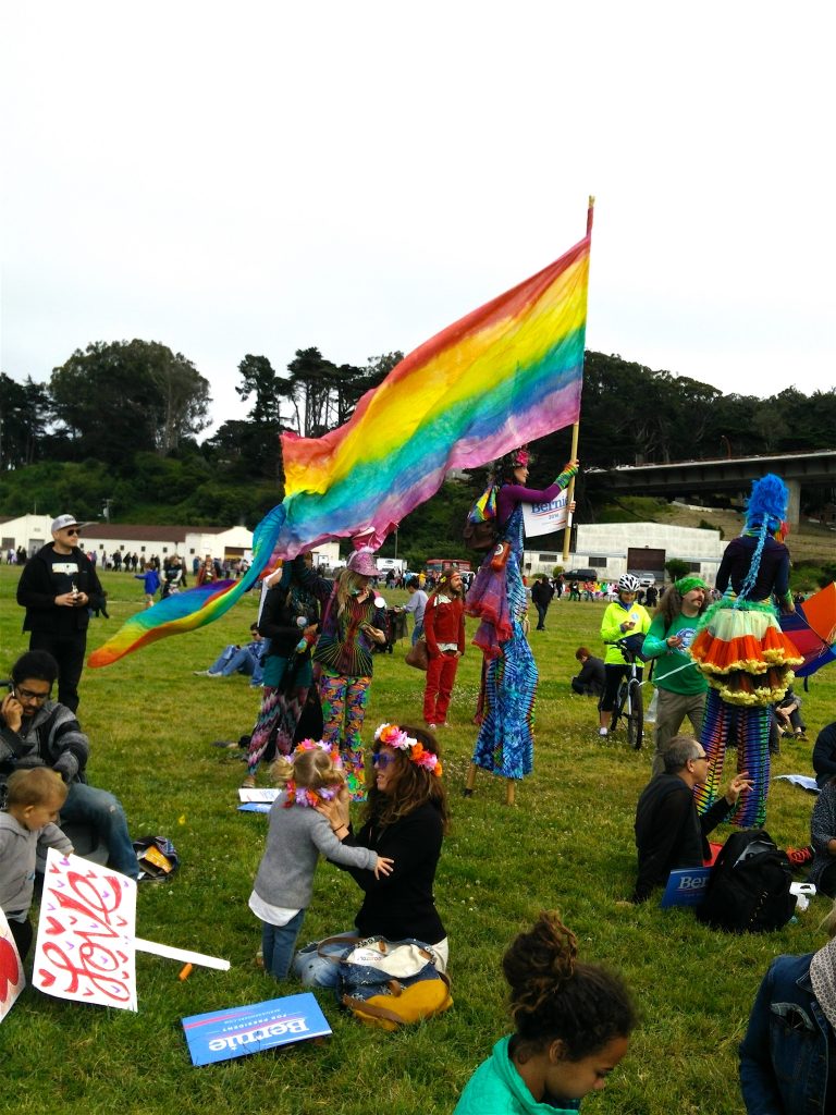 people in a park, people waiting for the Bernie Sanders rally at Crissy Field, Bernie Sanders supporters, Bernie Sanders rally, Bernie Sanders rally at Crissy Field, Crissy Field, San Francisco, Bernie Sanders, hippies, hipsters, mother and child in a park, mother and daughter, rainbow flag, gay rights, LGBT, men on stilts, Golden Gate Bridge, travel